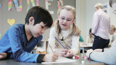 En gutt og jente fra 2. trinn som samarbeider om en matematikkoppgaver. De sitter i klasserommet. 