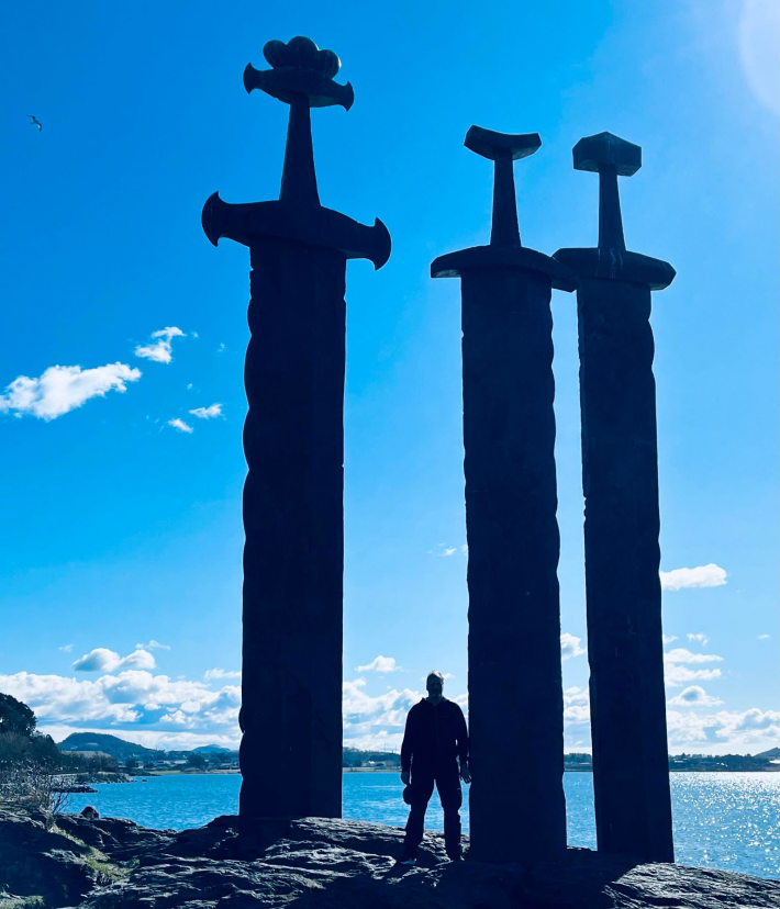 En mann står ved siden av de tre sverdene i Sverd i fjell som vi finner i Hafrsfjord.